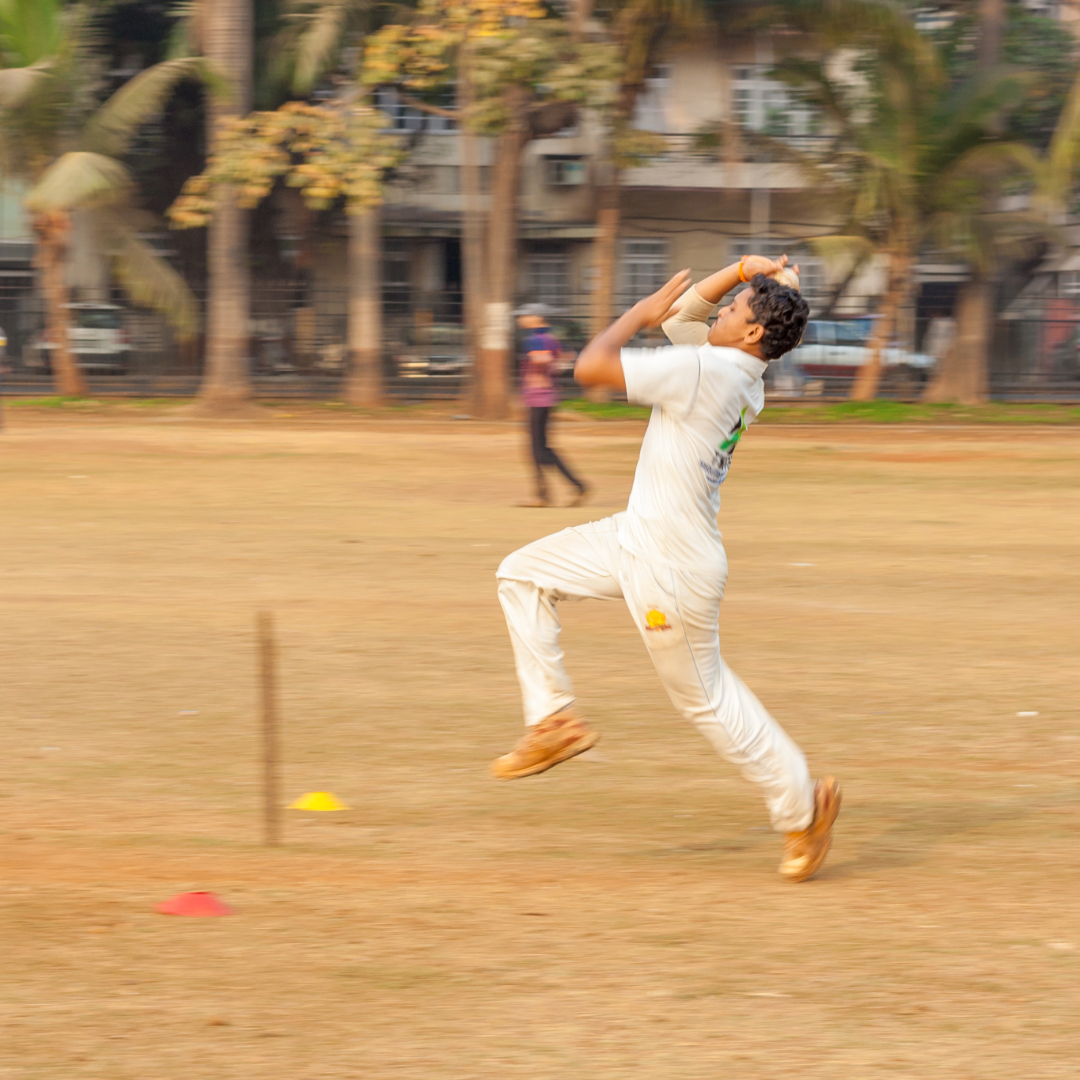 A male cricketer enters his delivery stride playing on an urban pitch