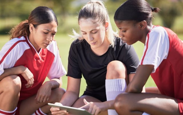 Coach talking to two participants, showing them a plan on a tablet