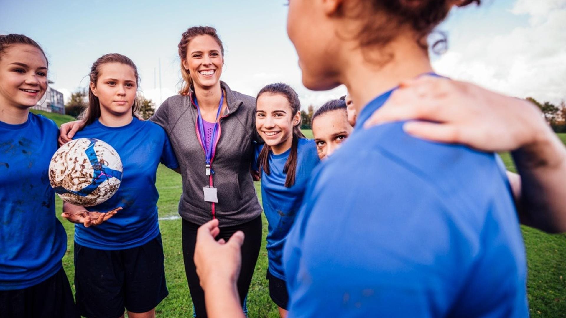 A football coach and her players gather together