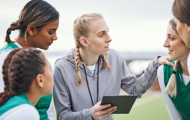 Coach talking to participants in a team huddle, holding tablet