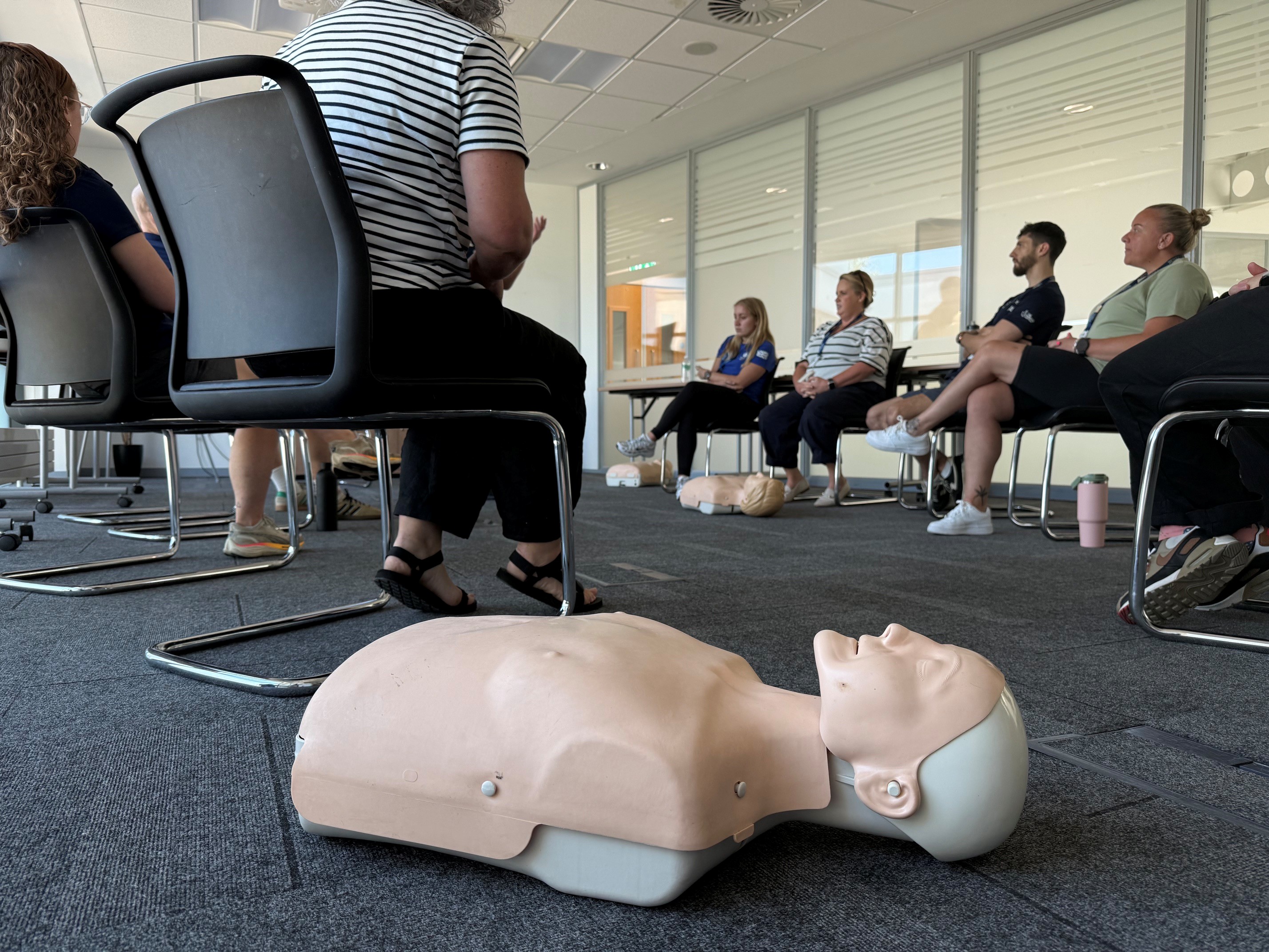 CPR training manikin in the foreground during a UK Coaching First Aid workshop for British Cycling staff and volunteers.