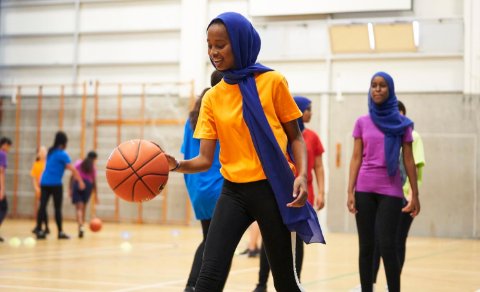 Young participants wearing hijabs playing basketball