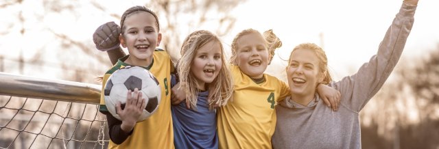 girls-and-coach-celebrating-with-football