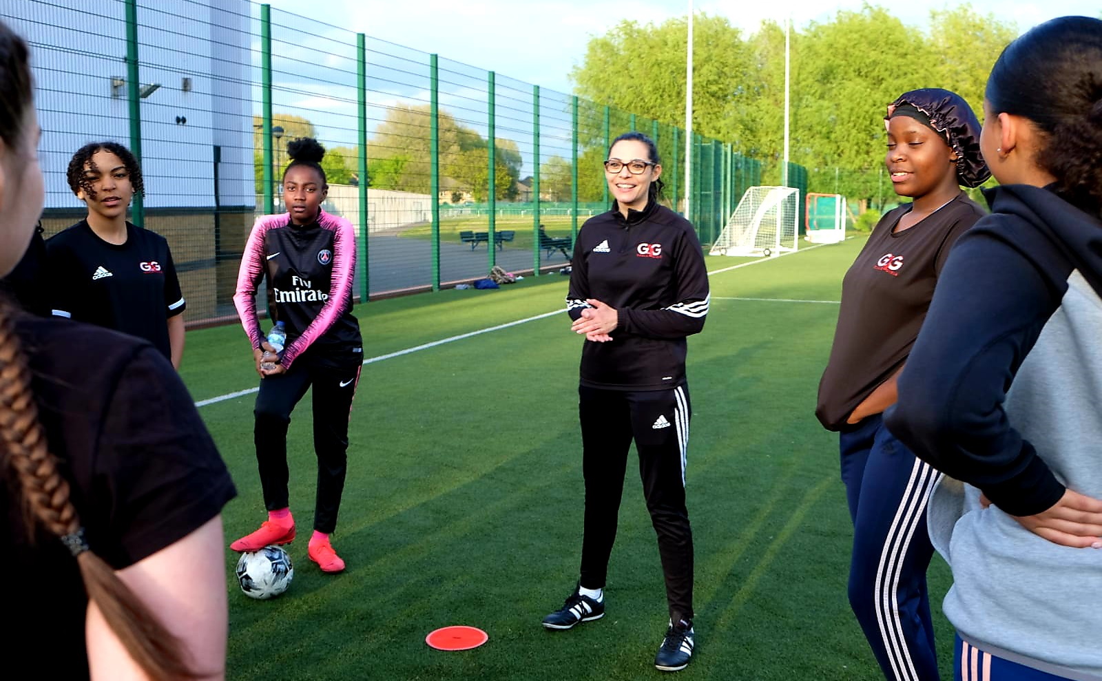 A female football coach addresses a group of participants.